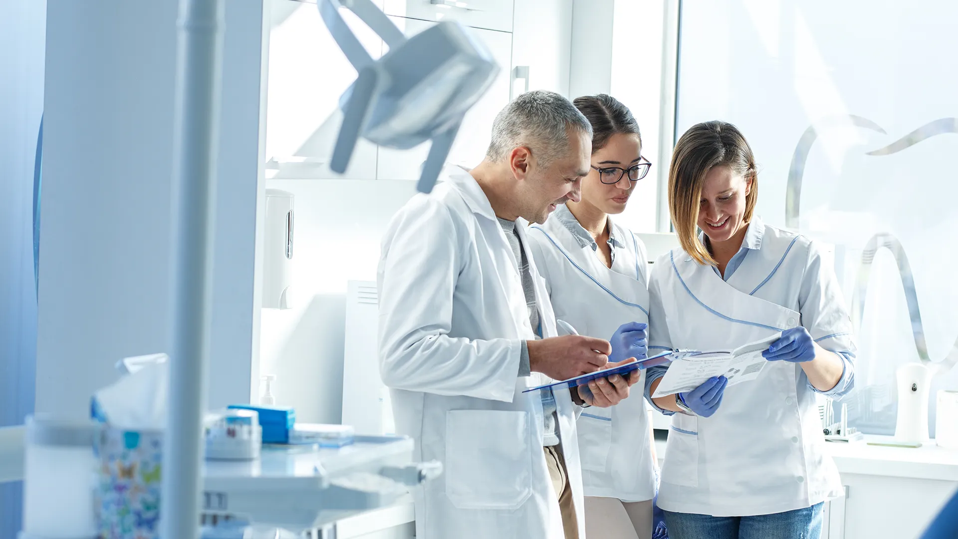 Three dentists smiling while looking at a document together.