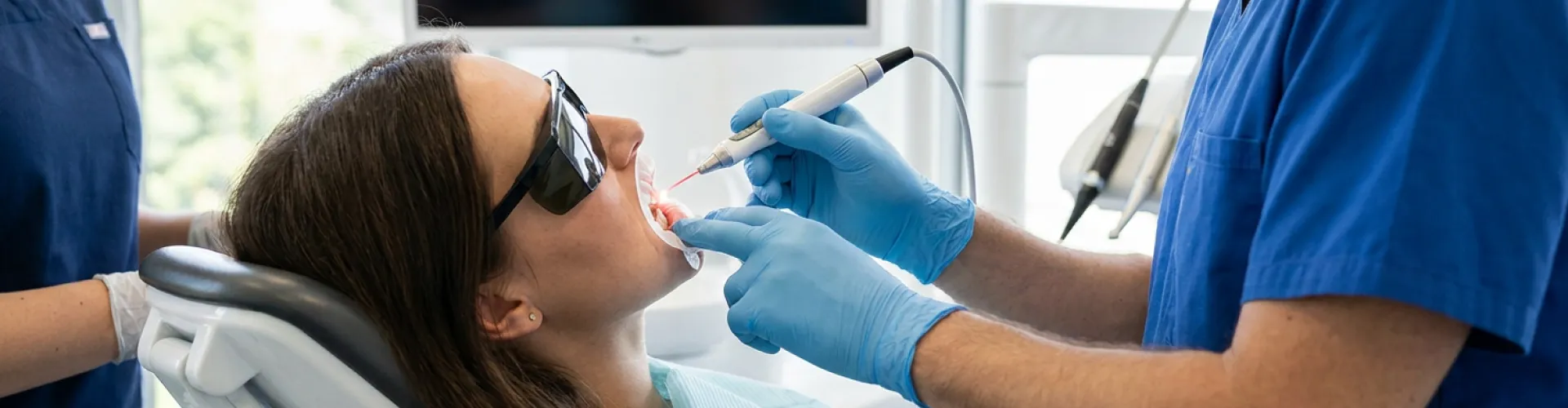 Patient undergoing laser gum contouring treatment while wearing protective eyewear as a dentist carefully reshapes the gumline to improve smile aesthetics and oral health.