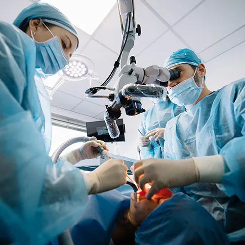 two dentists using dental tools in patients mouth in surgery room
