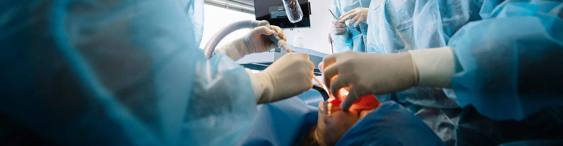 two dentists using dental tools in patients mouth in surgery room