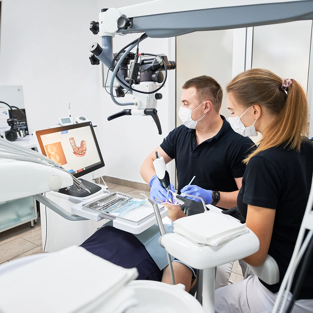 Dentist and dental assistant working with a patient while looking at a screen.