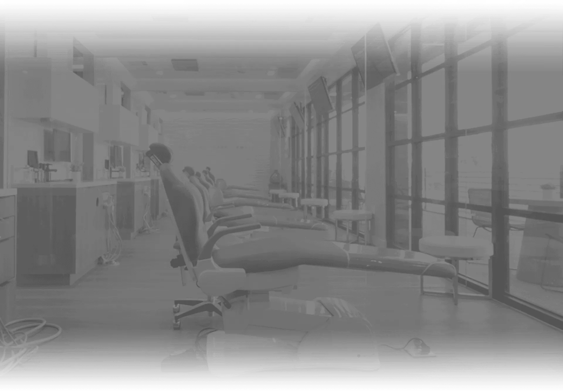 Grayscale image of a dentist's office showing dental chairs and equipment.