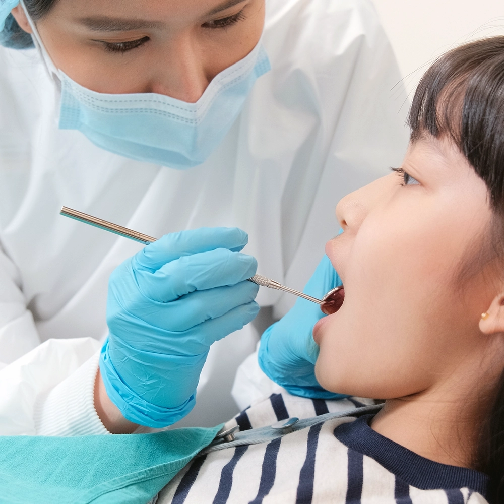 A dentist examining a patient’s mouth with a dental mirror.