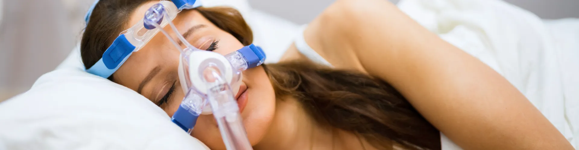 Woman laying on her side wearing sleep apnea device.