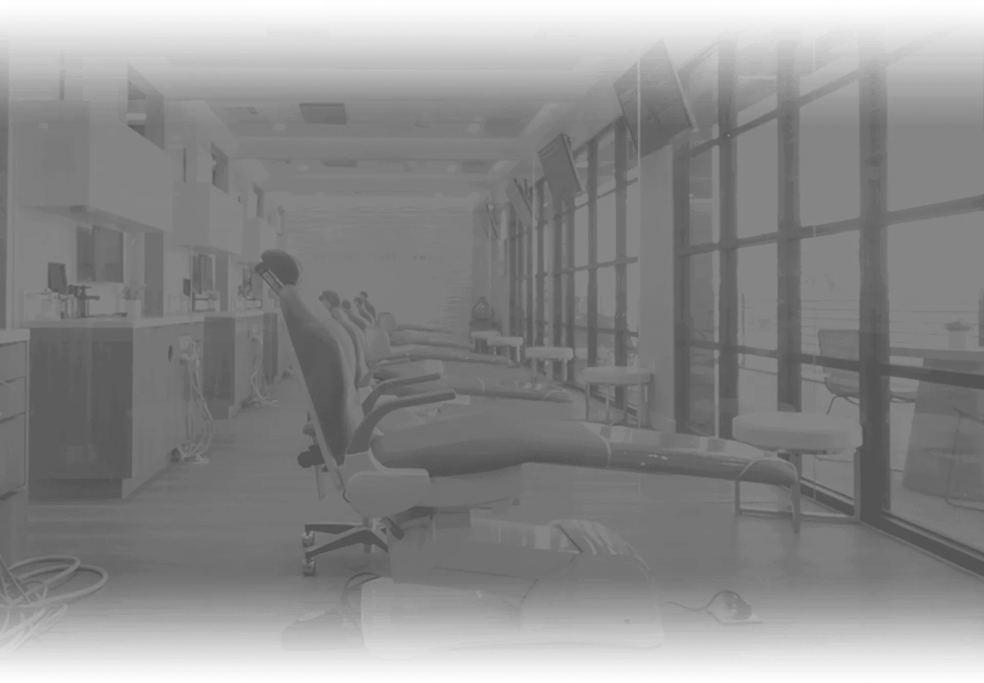 Grayscale image of a dentist's office showing dental chairs and equipment.