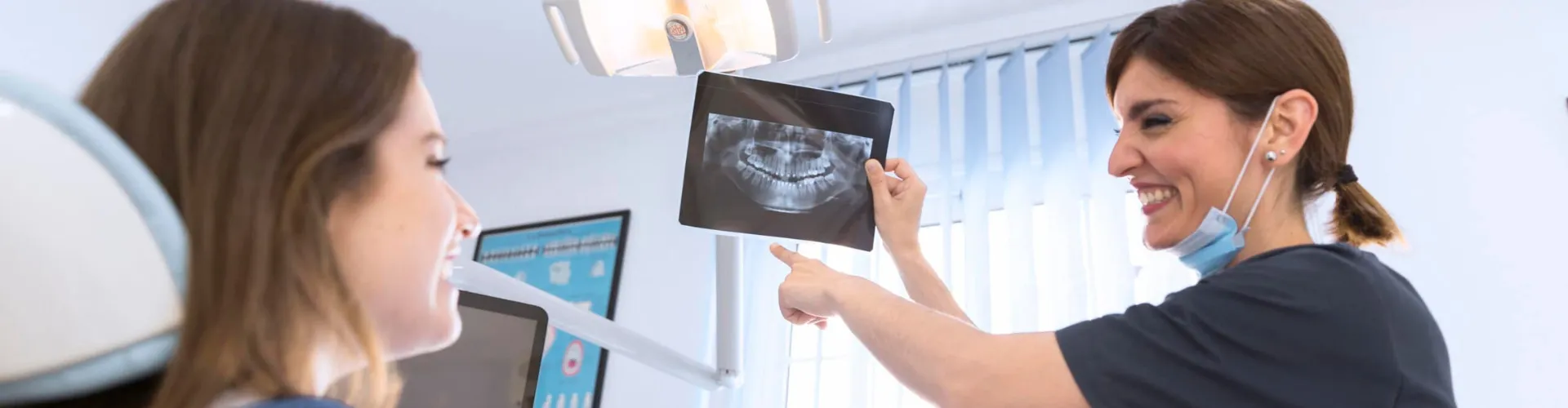 Female dental professional showing dental X-ray to female patient.