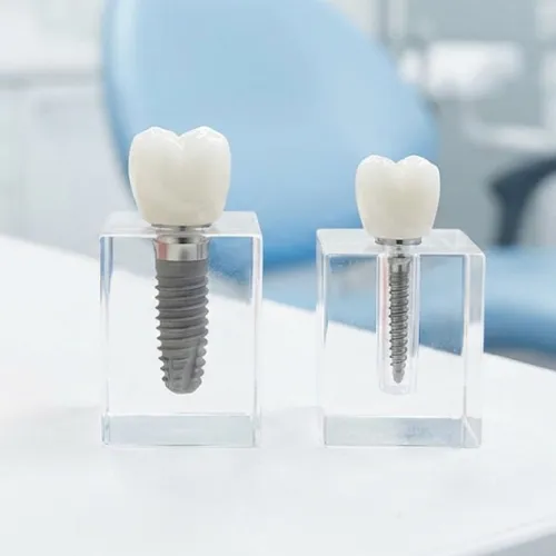 Dental implant beside mini dental implant on white surface.
