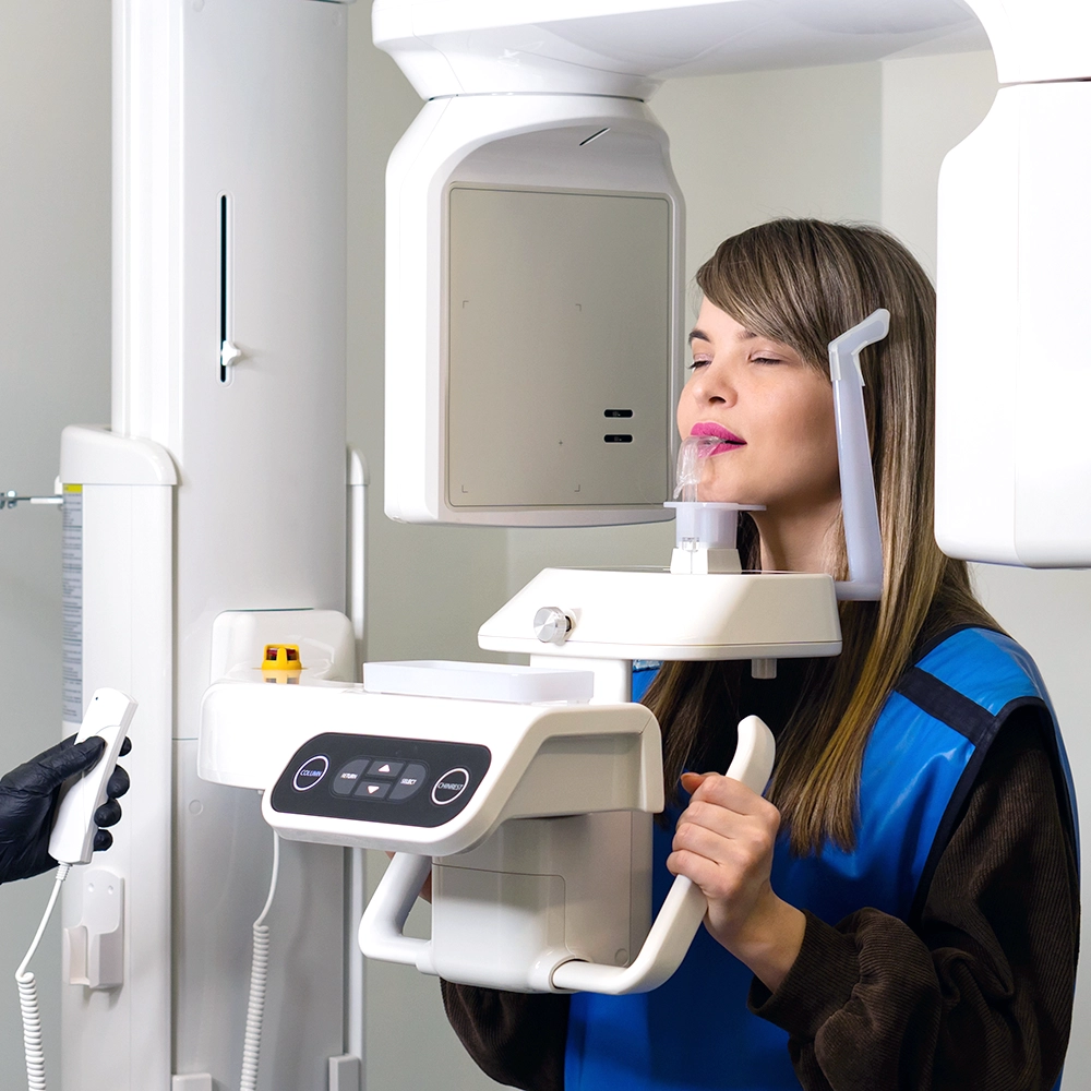Woman undergoing a panoramic dental X-ray in a machine that rotates around her head.