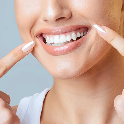 woman pointing at her smile with both index fingers