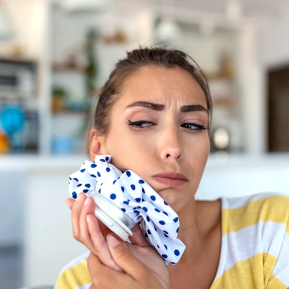Girl holding a bag of ice to her face to relieve a toothache.