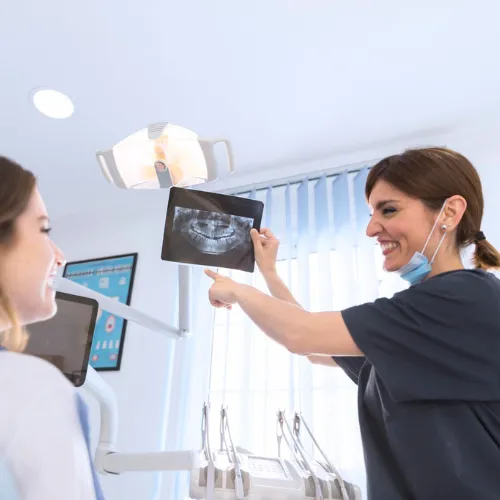 Female dental professional showing dental X-ray to female patient.