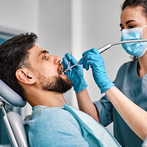 female dentist using dental tools in male patient's mouth