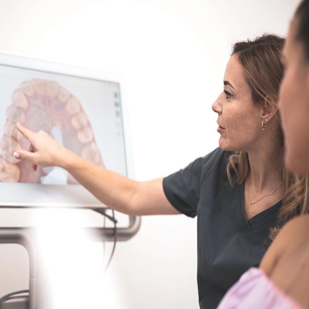 Dentist showing information on a screen displaying teeth.