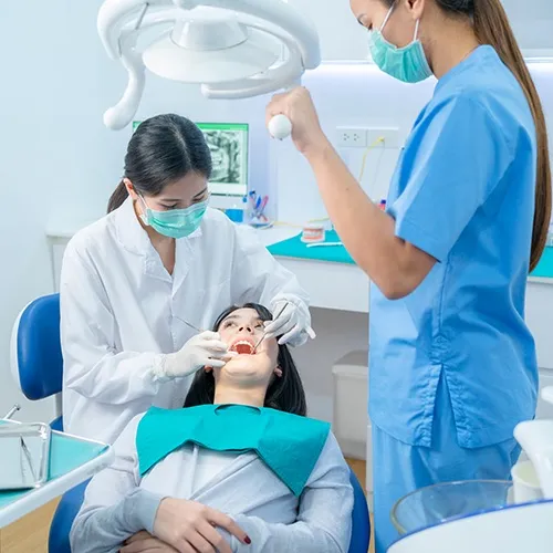 dental team using dental tools in patient's mouth