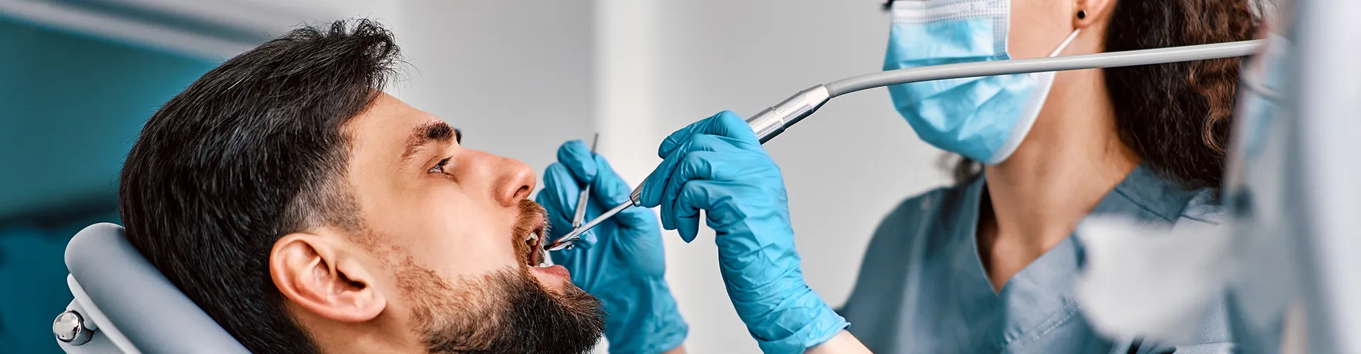 female dentist using dental tools in male patient's mouth